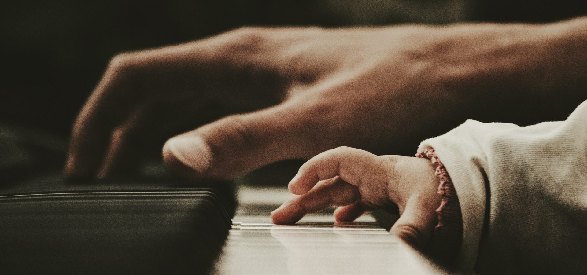 Hands of an adult and a child playing the piano togehter